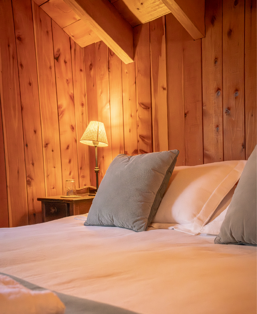 Detalle cálido de la cama principal de la suite cuádruple